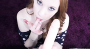 Beautiful chick wearing blue and white polka dotted dress gets on her knees and sucks a big flesh dildo before she rubs it between her hot boobs on a purple carpet.